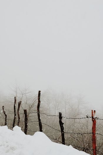 Fence on snow covered field against sky