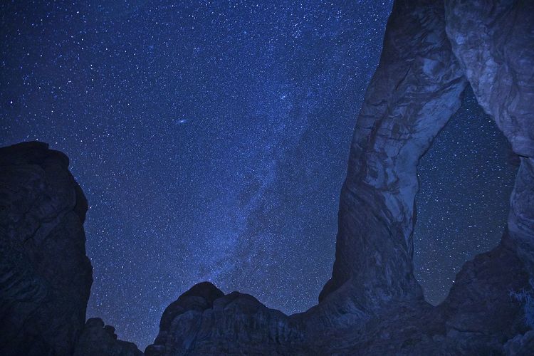 Low angle view of rock formation against star field at night
