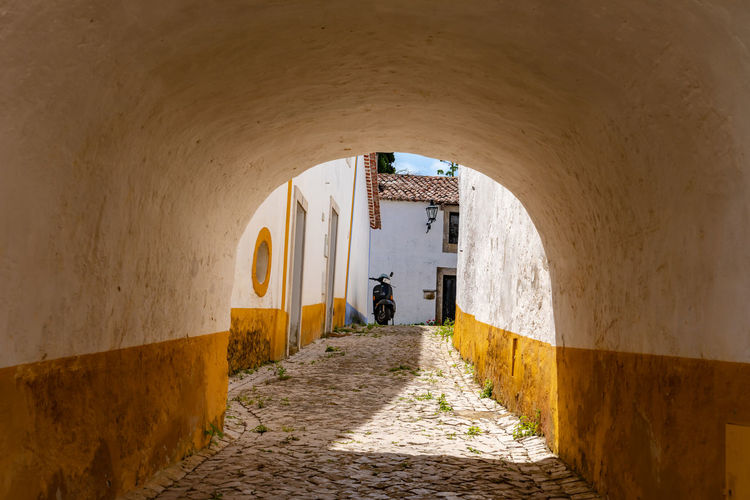 A narrow lane leads to houses via a passage in the city walls, Óbidos castle, portugal