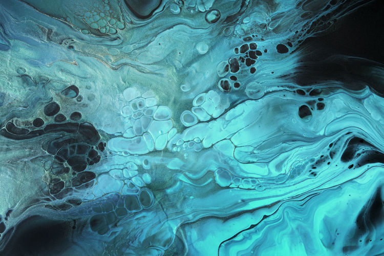 Fluid art. fluorescent blue waves with golden particles on black background. marble effect