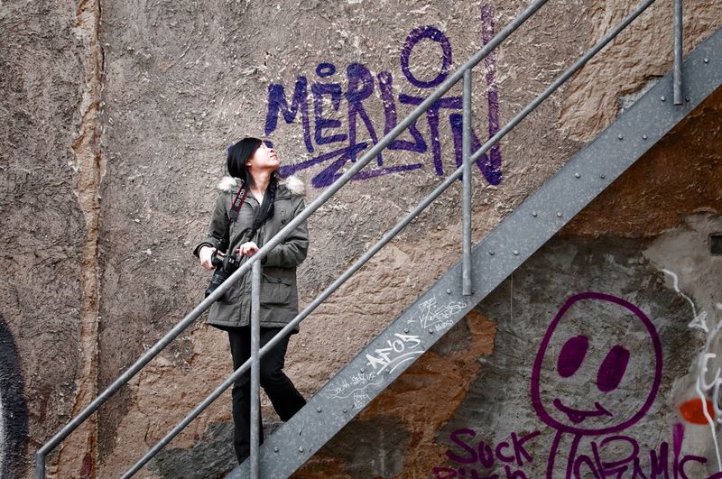 Young woman looking at graffiti on wall while moving downstairs
