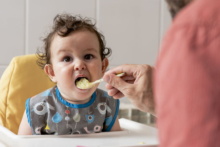 Portrait of cute baby eating food at home