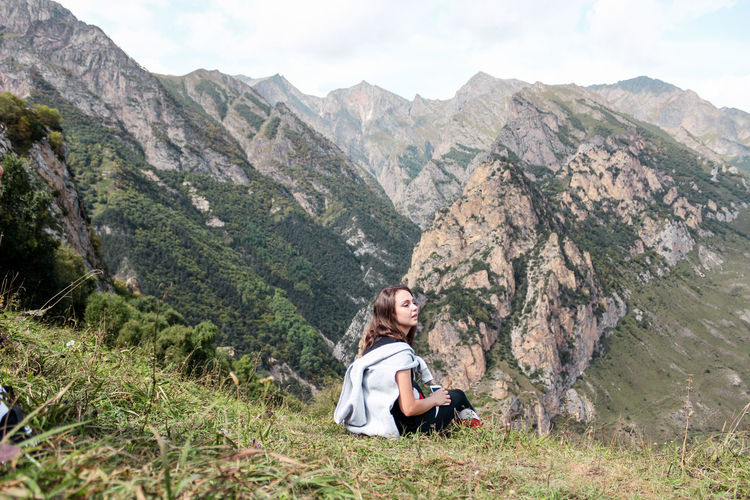 Young woman sitting against mountain range
