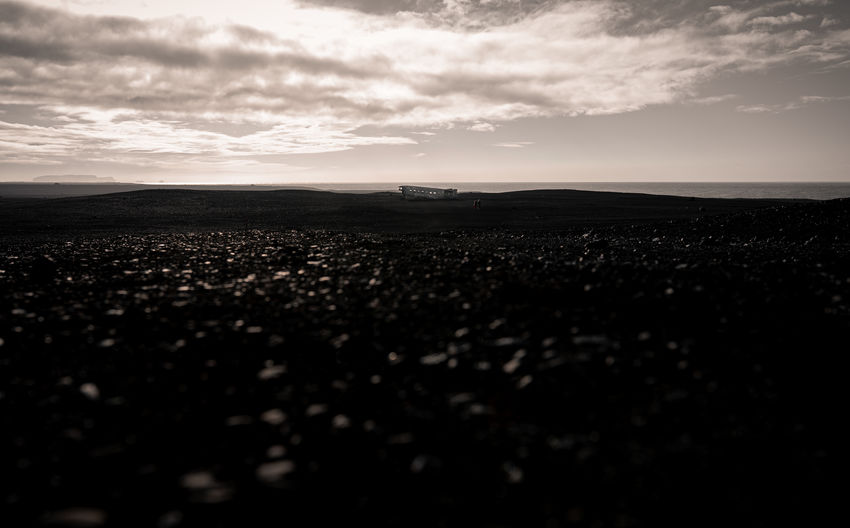 Black and white of vast volcanic solheimasandur beach with remains from crashed aircraft in iceland