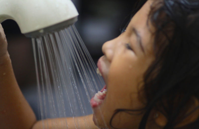Close-up of girl taking bath with shower