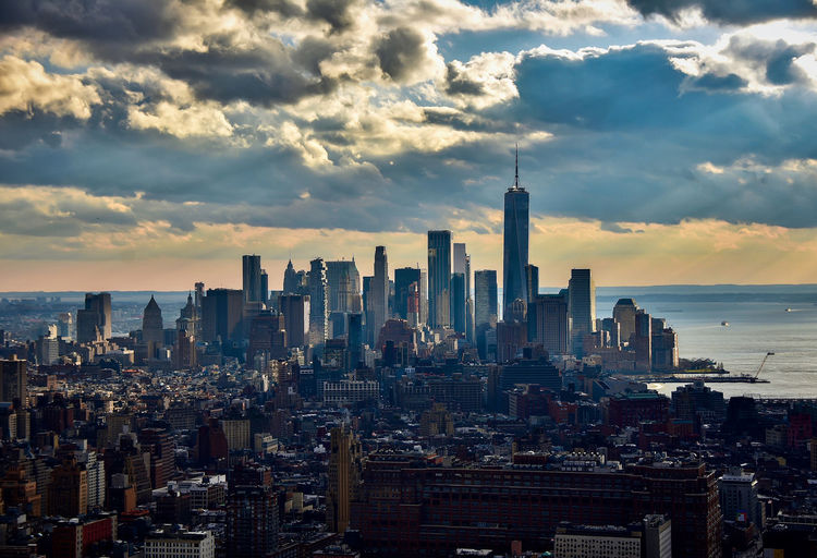 Modern buildings in city against sky during sunset. nyc lower manhattan with sun rays