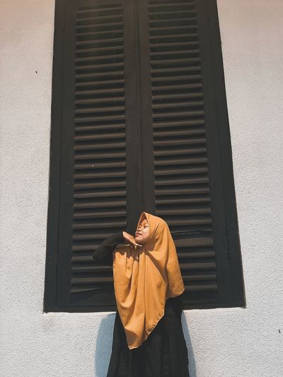 Woman wearing hijab standing by window outdoors