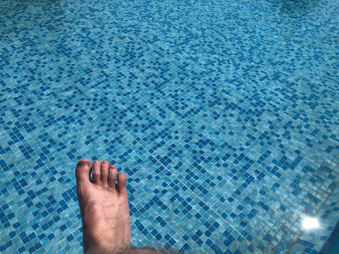 Low section of person legs in swimming pool