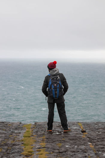 Rear view of man standing in sea against sky