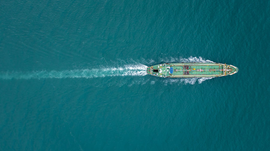 Aerial top view oil ship tanker sailing full speed with beautiful wave and splash water in line 