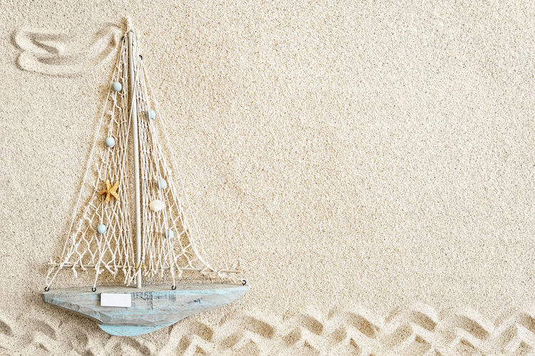 Sand background with small wooden boat, top view, copy space