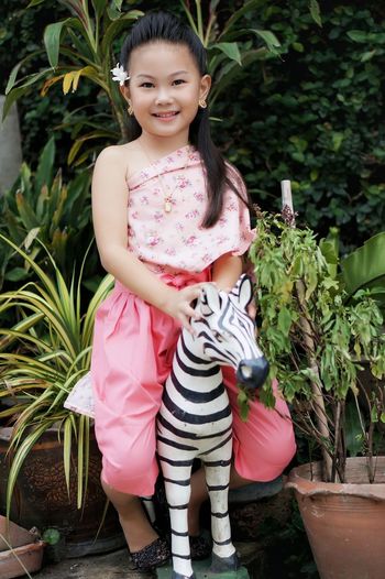 Full length of smiling girl standing against plants