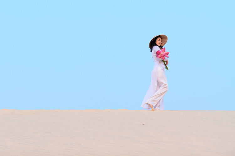 Full length of woman on sand dune against clear sky