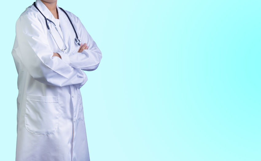 Midsection of doctor standing against blue background