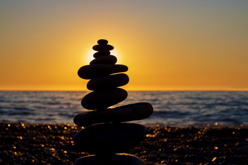 Stack of pebbles on beach during sunset