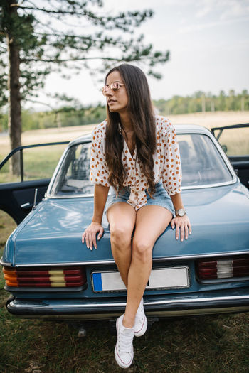 Retro girl sitting on the trunk of a car.