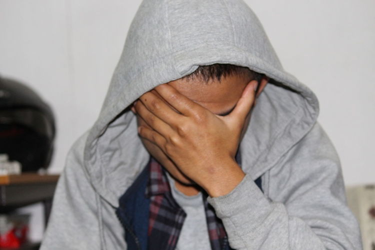 Stressed young man with head in hand wearing hooded jacket