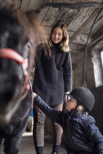 Mother with daughter preparing pony for ride