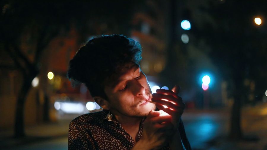 Portrait of young man using smart phone on street at night