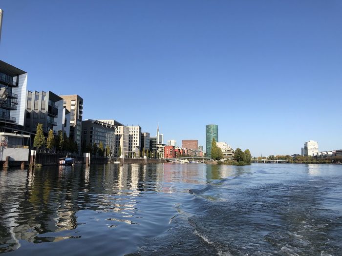 River and buildings against clear blue sky