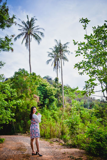 Rear view of woman walking on palm trees