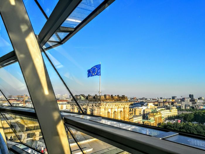 European union flag waving in city seen through window