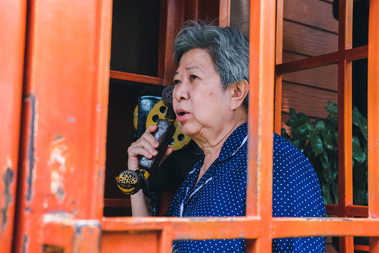 Senior woman talking on phone in telephone booth