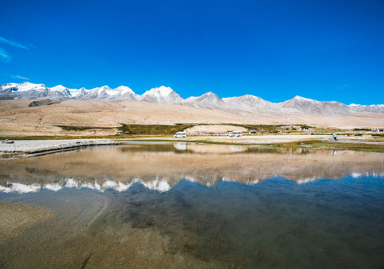 Scenic view of lake and mountains against blue sky