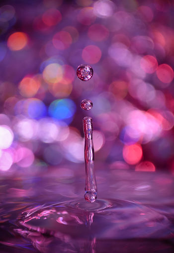 Close-up of drop falling on illuminated water