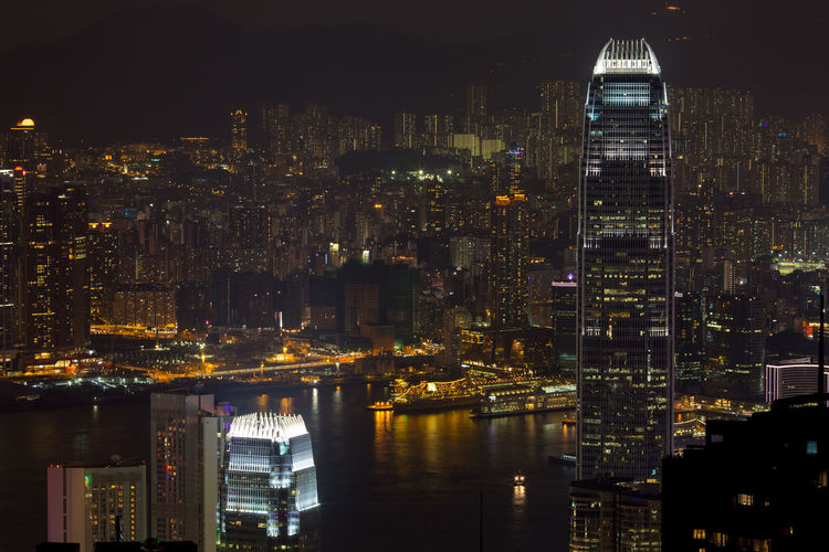 Buildings at victoria harbour in illuminated city at night