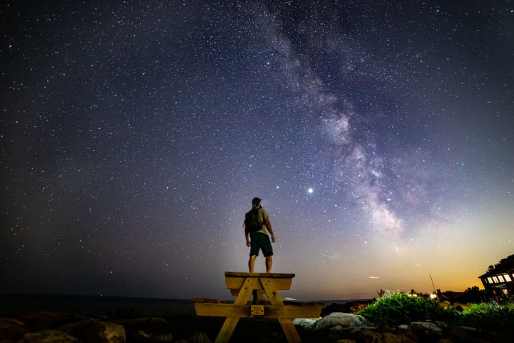 Silhouette of man star gazing on a picnic table under the milkyway.