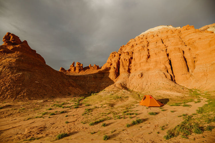 An orange tent sits at the base of red sandstone formations in utah