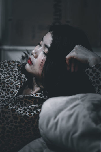 Midsection of woman resting on bed at home