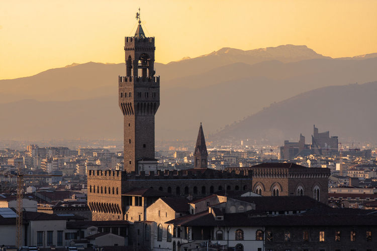 Buildings in town against mountains during sunset