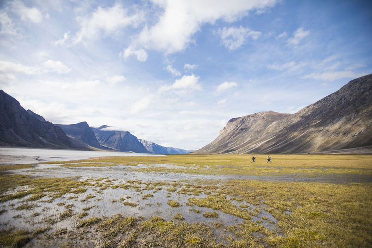 Two backpackers cross wet tundra in akshayak pass.