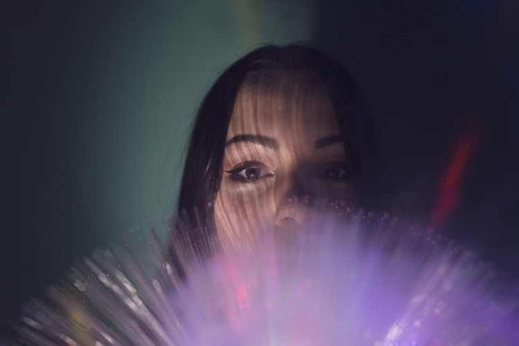 Close-up portrait of young woman with fiber optic