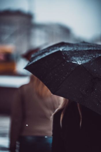 Midsection of woman carrying umbrella while walking on street during monsoon