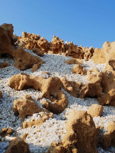 Close-up of sand on beach against clear blue sky