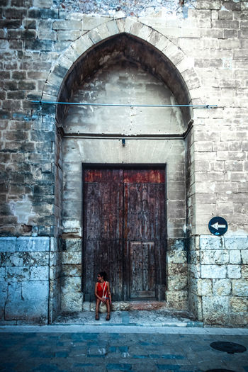 Man standing against door of old building