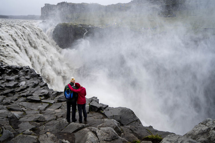 Couple looking at waterfall while standing on mountain
