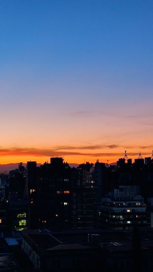 High angle view of silhouette buildings against clear sky at sunset