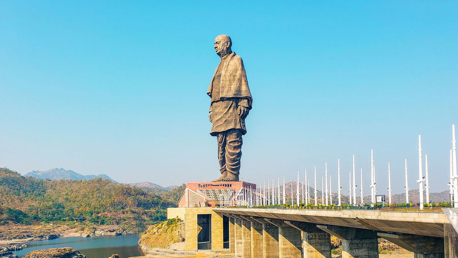 Man standing on bridge against clear blue sky