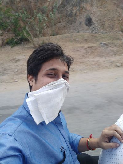 Portrait of young man with handkerchief on face against road