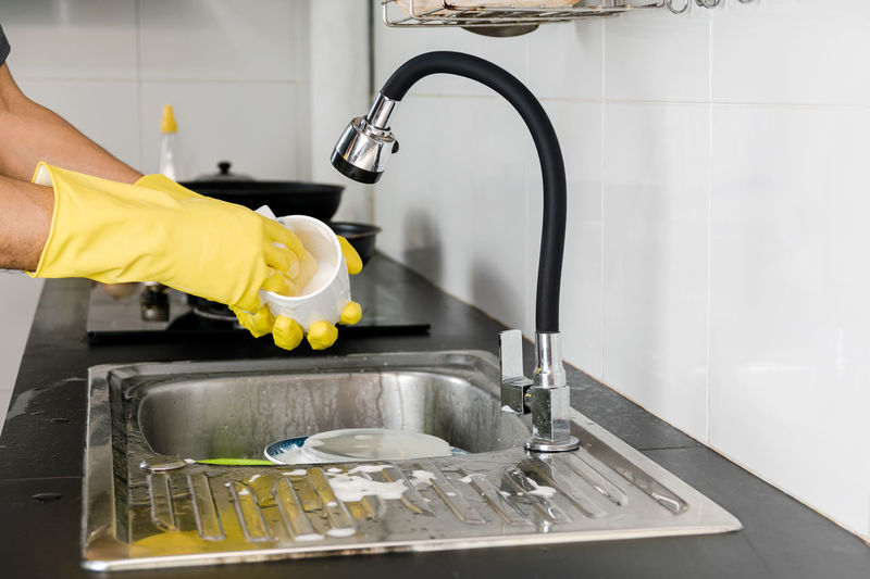 Midsection of man with faucet in kitchen at home