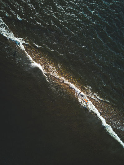 High angle aerial view of two surfers in the sea.
