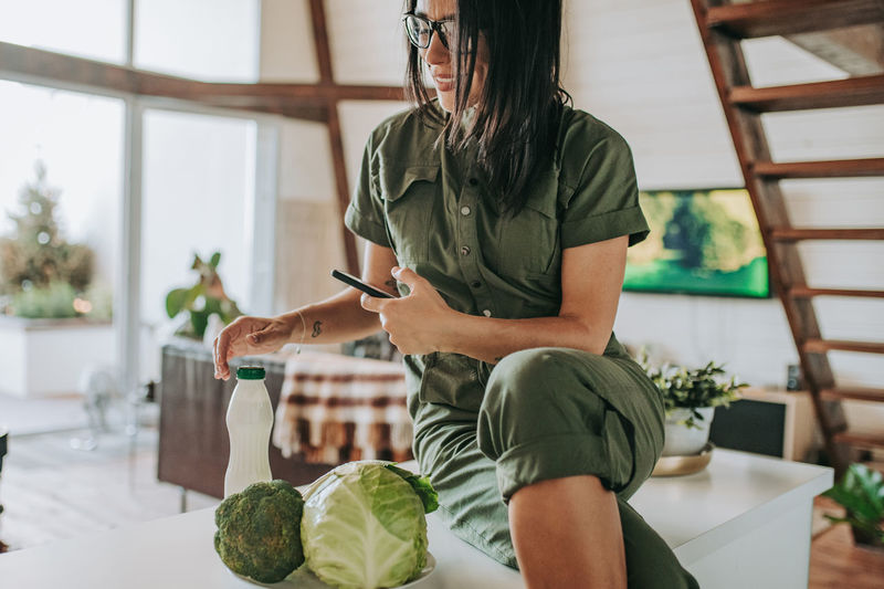 Midsection of woman holding while sitting on table at home