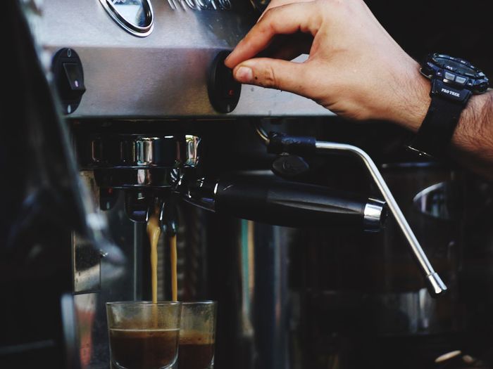 Close-up of hand pouring coffee in cafe