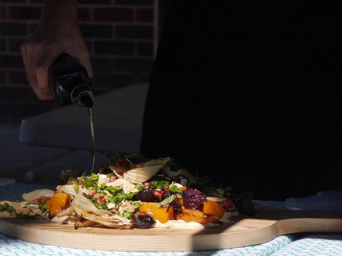 Cropped hand pouring oil on salad at home