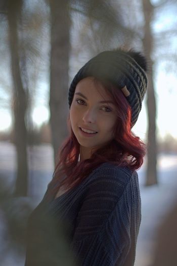 Portrait of smiling young woman in forest during winter
