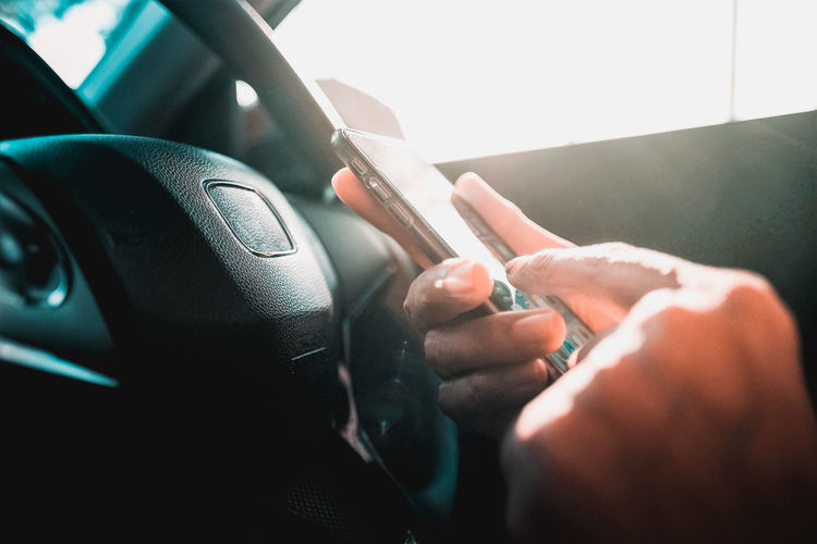 Close-up of person holding smart phone in car